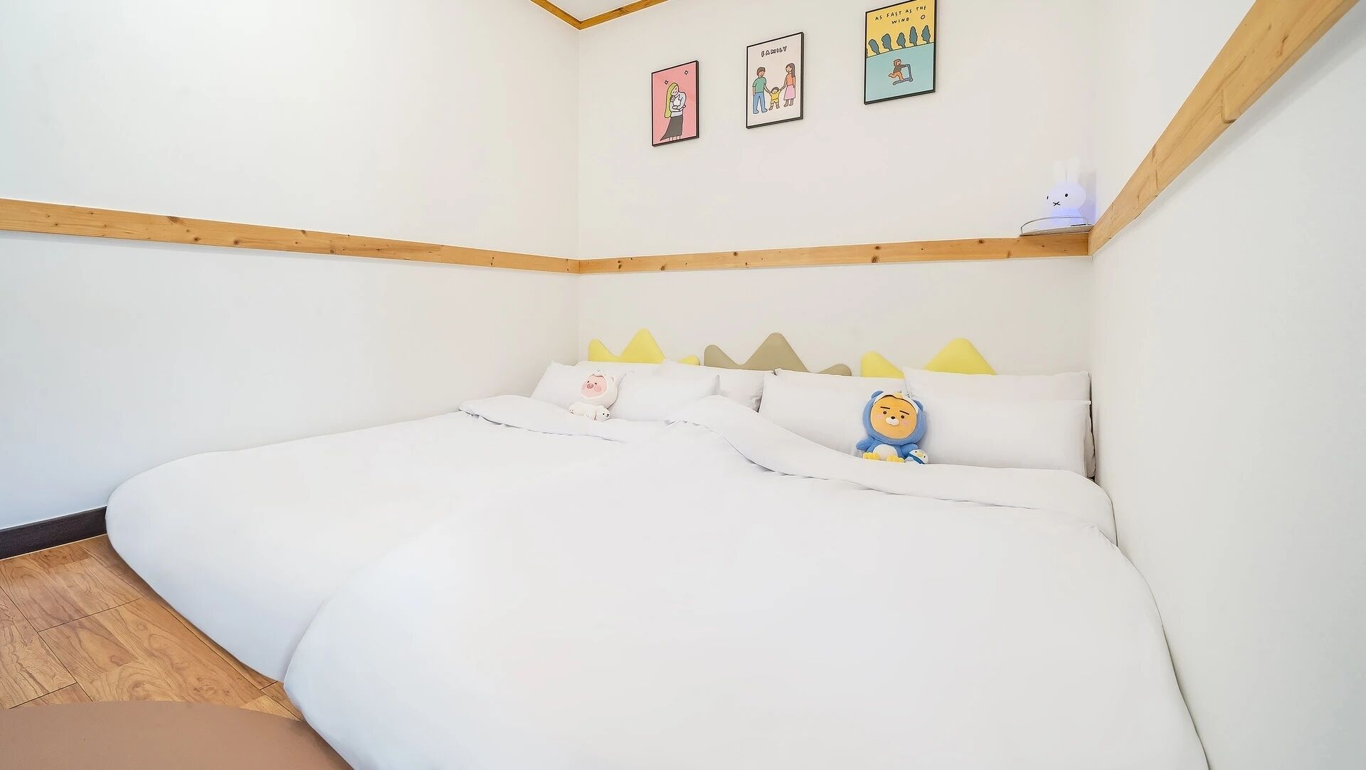Un dormitorio con una cama grande, cabecera de madera y una pequeña estantería con una lámpara.