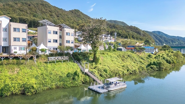 Un hotel junto al río con un muelle para barcos, una escalera que baja al agua y un cartel que dice 'Eldorado'.
