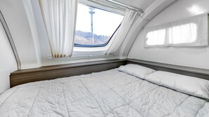 A bedroom with a large bed, a window with curtains, and a view of a tower.