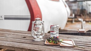 A wooden table with a metal lantern, a can of Budweiser, and a plate with grapes.