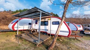 A caravan park with two caravans, each with a covered patio area and a picnic table. - Gapeyong Unak Holiday Caravan (Gapyeong)