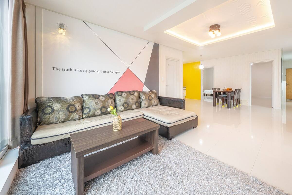 A modern living room with a sofa, coffee table, and a dining area with chairs and a table.