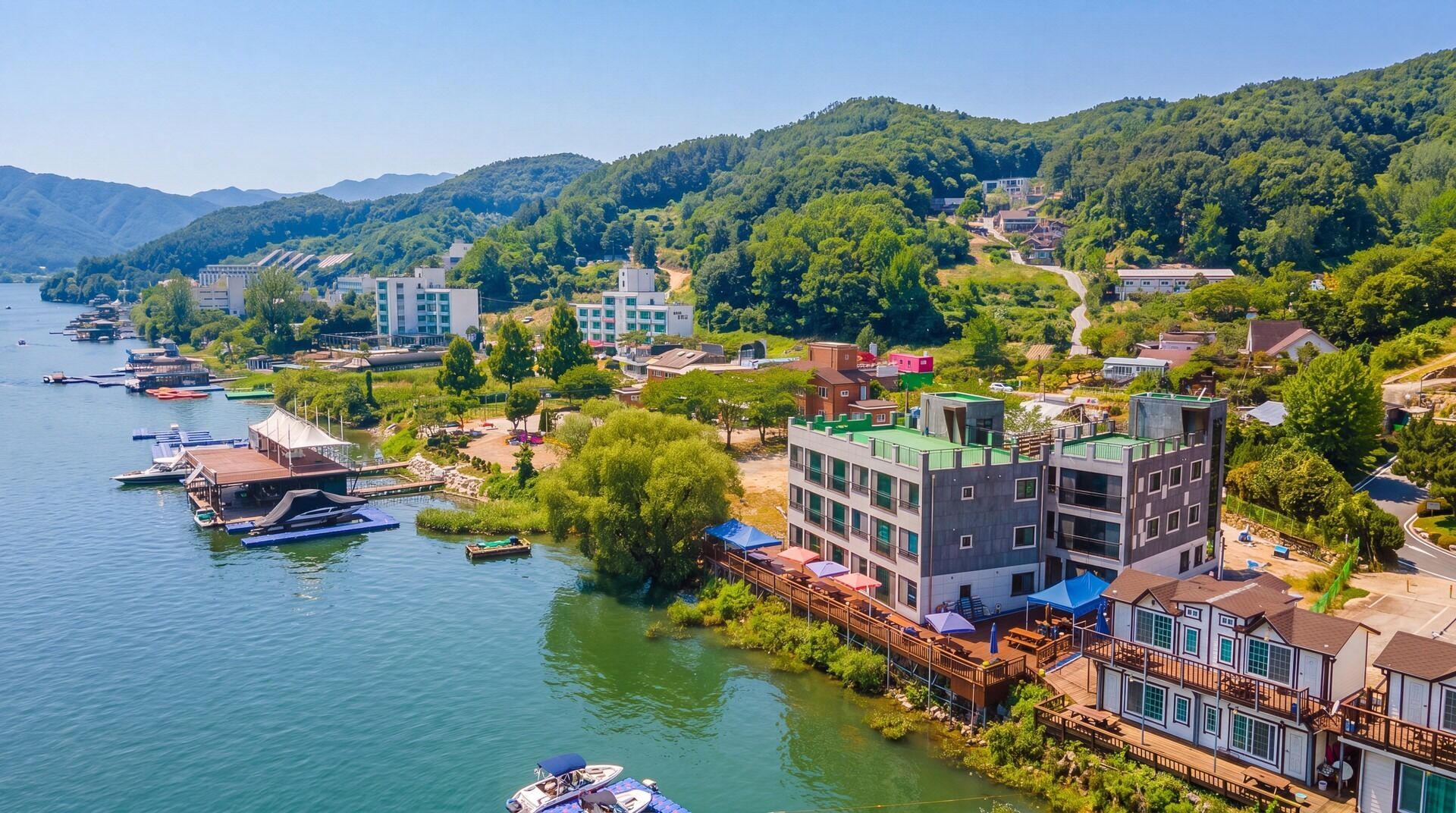 Un pueblo a orillas del río, con edificios a lo largo de la orilla, un muelle con barcos y un puente que une las zonas.