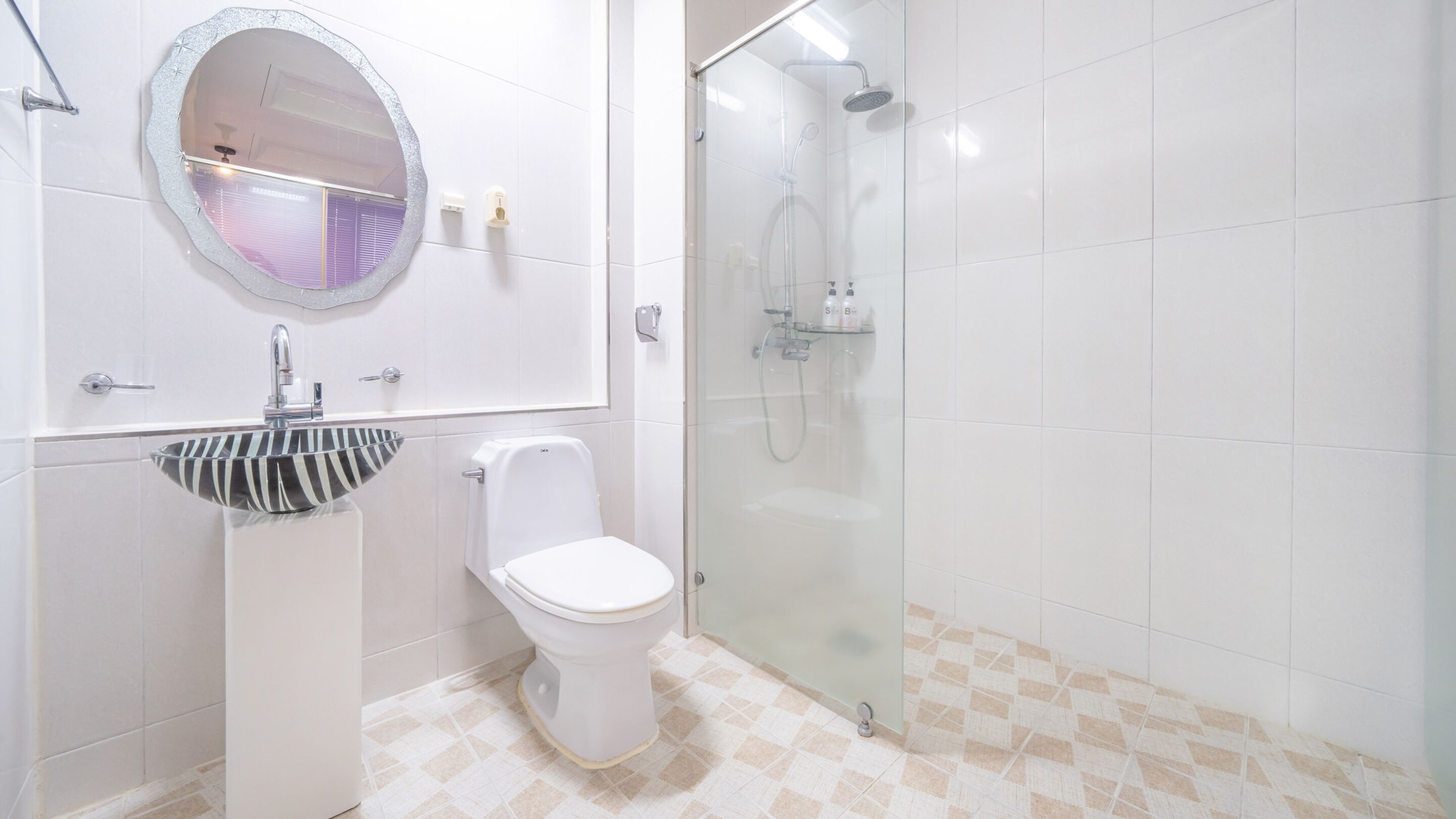 Une salle de bain moderne avec un lavabo, des toilettes et une douche, le tout de couleur blanche.