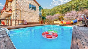 Una piscina con un flotador, un tobogán y una cubierta de madera.