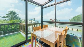 Un comedor con una mesa y sillas, ventanas amplias y vistas al mar y edificios.