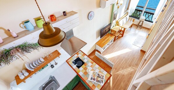 A kitchen with a wooden table, a hanging light fixture, and a window overlooking the sea. - Ganghwa Hana & Alice spa Pension (Incheon)