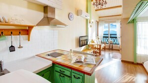 A kitchen with a tiled backsplash, a central island, and green cabinets. - Ganghwa Hana & Alice spa Pension (Incheon)