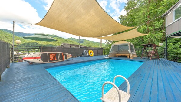 A swimming pool with a wooden deck, a tent, and a surfboard. - Gapyeong Myeonyeokgongbang Private Villa (Gapyeong)