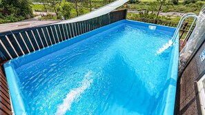 A rectangular swimming pool with a wooden deck and metal railing, surrounded by greenery. - Gapyeong Myeonyeokgongbang Private Villa (Gapyeong)