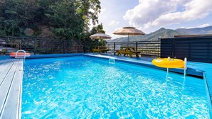 A swimming pool with clear blue water, surrounded by a wooden deck and yellow lounge chairs. - Gapyeong Myeonyeokgongbang Private Villa (Gapyeong)