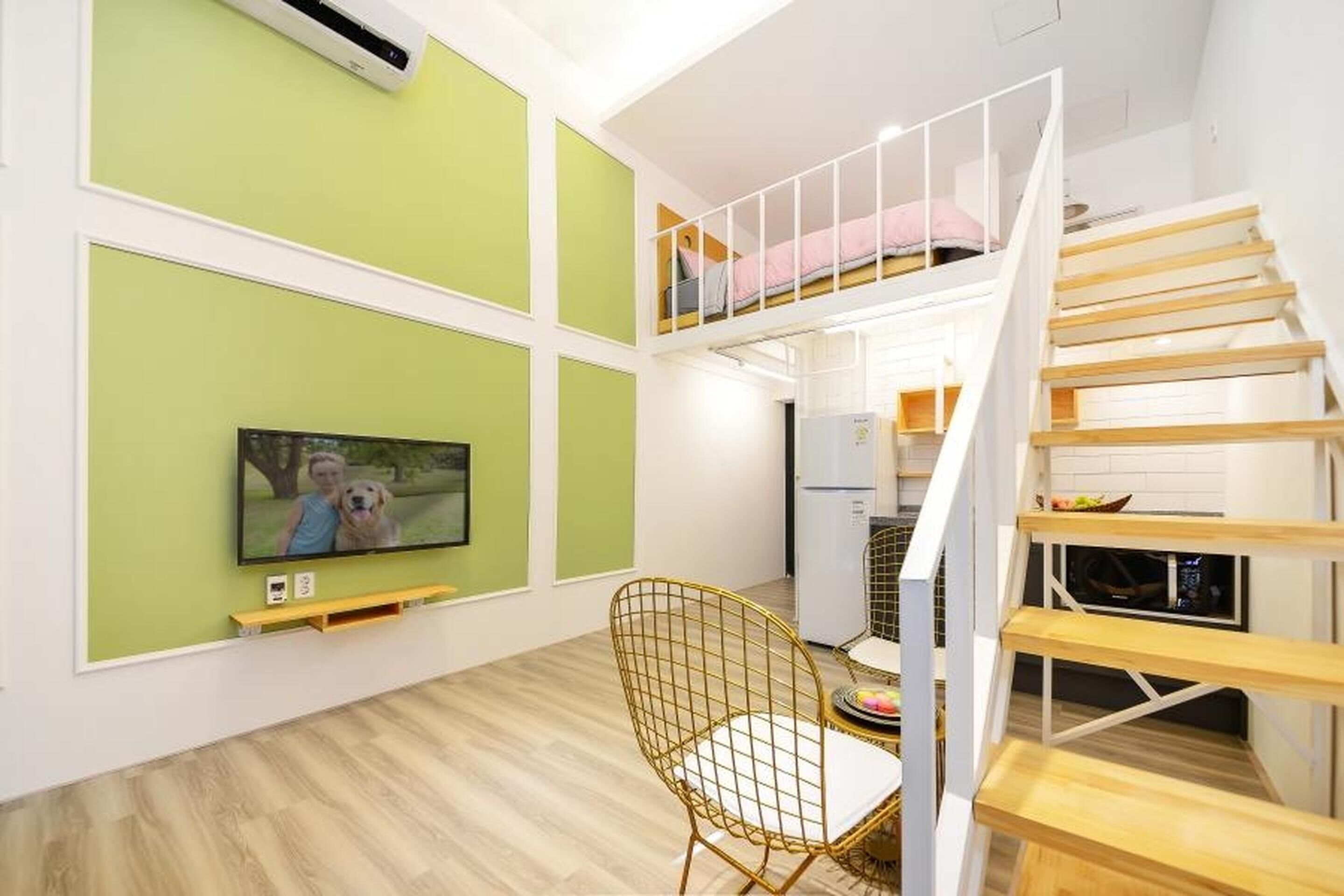 A modern apartment with a loft bedroom, a dining area with a TV, and a staircase.
