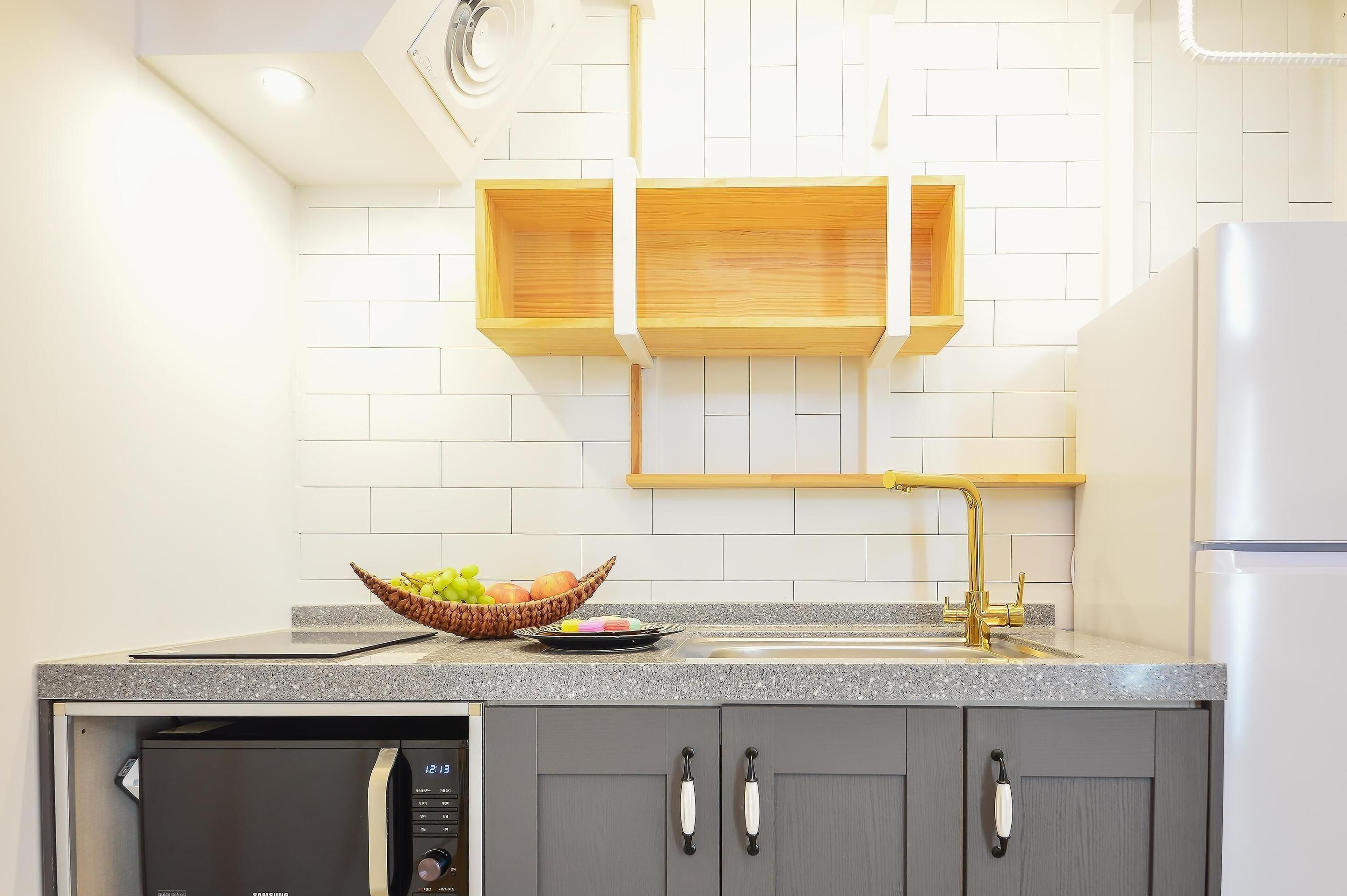 A kitchen with a granite countertop, a dishwasher, a sink with a gold faucet, and wooden cabinets.