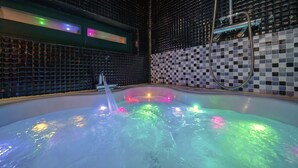 A hot tub with colorful lights, surrounded by black and white mosaic tiles. - Chuncheon Vishop Pension (Chuncheon)