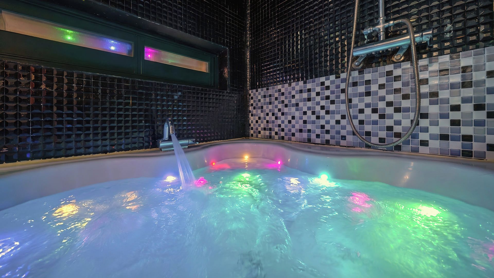Un jacuzzi con luces de colores, rodeado de paredes con azulejos.