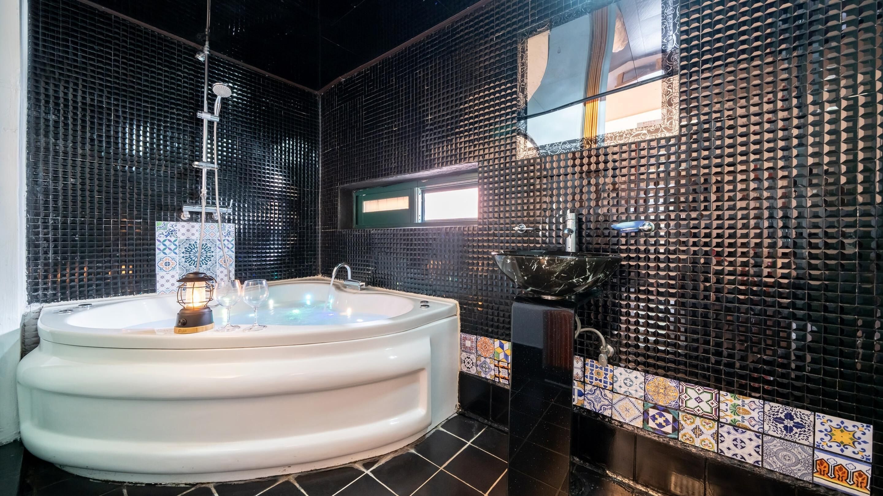 A modern bathroom with a freestanding bathtub, a large mirror, and a decorative sink.