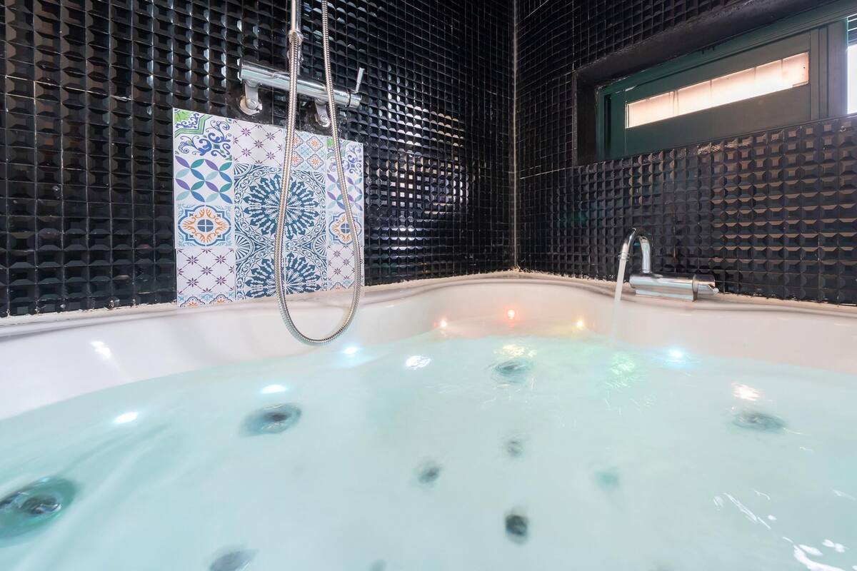 A modern bathroom with a bathtub, a shower area, and decorative tiles.