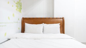 A neatly made bed with a wooden headboard and white bedding. - Chuncheon Vishop Pension (Chuncheon)