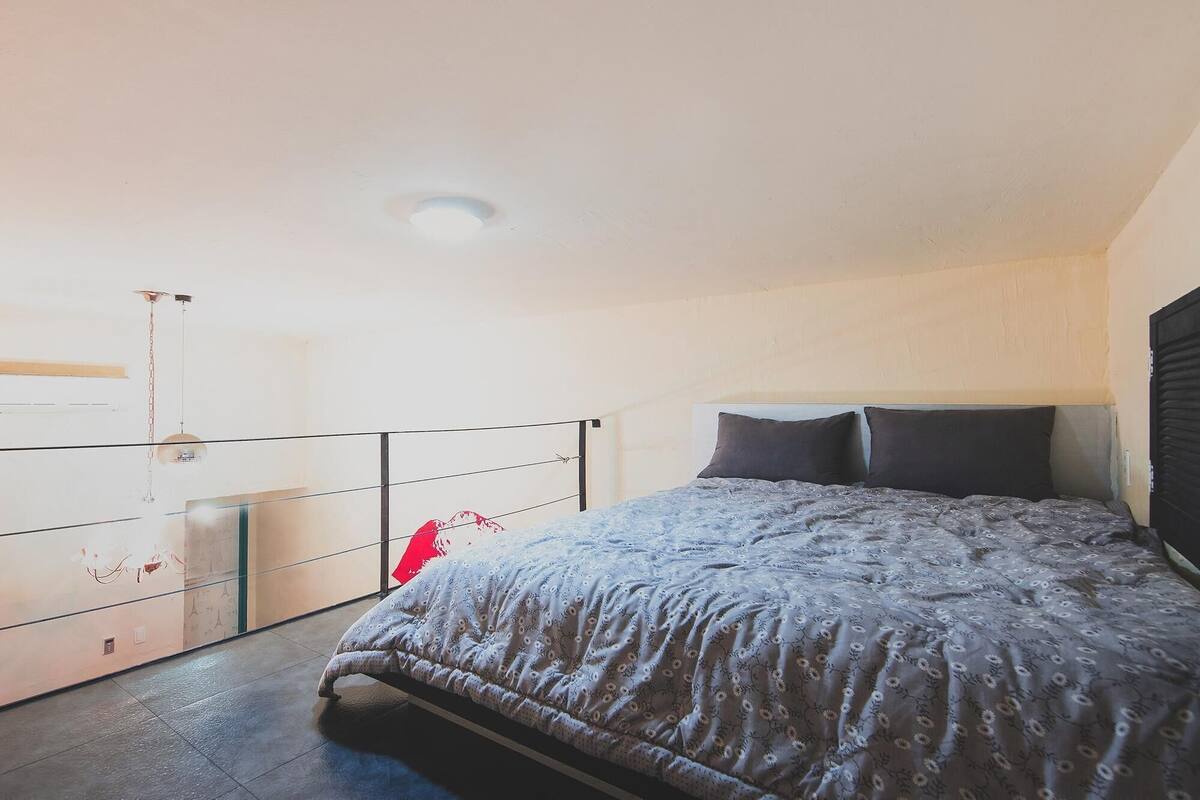 A bedroom with a bed, a headboard, a window, and a ceiling light.