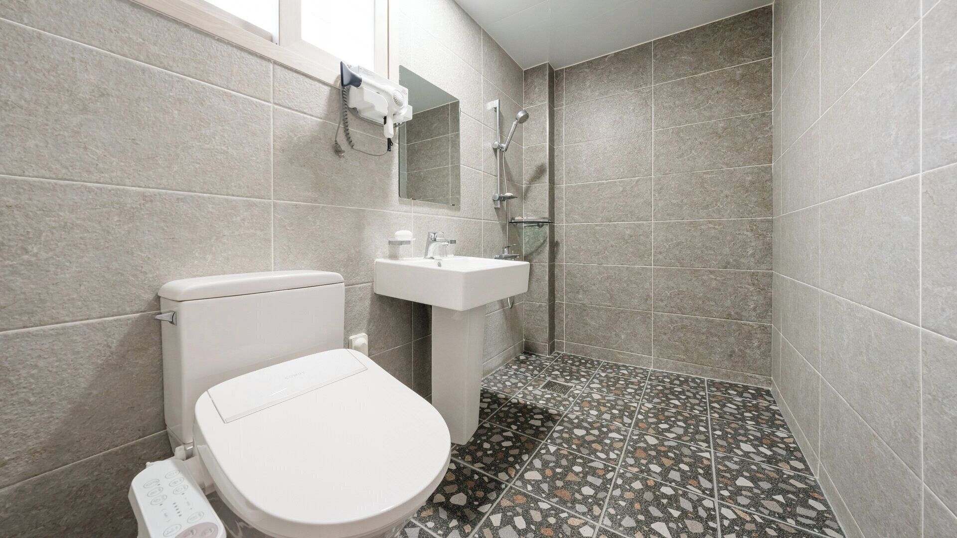 A bathroom with a toilet, sink, and shower.