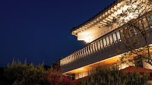 Un bâtiment doté d’un balcon, d’un toit muni d’une rambarde et d’un ciel nocturne.