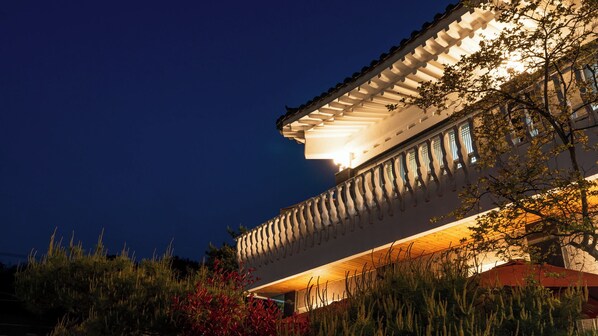 A building with a balcony, a roof with a railing, and a night sky. - Gyeongju Soraedanga Pension (Gyeongju)