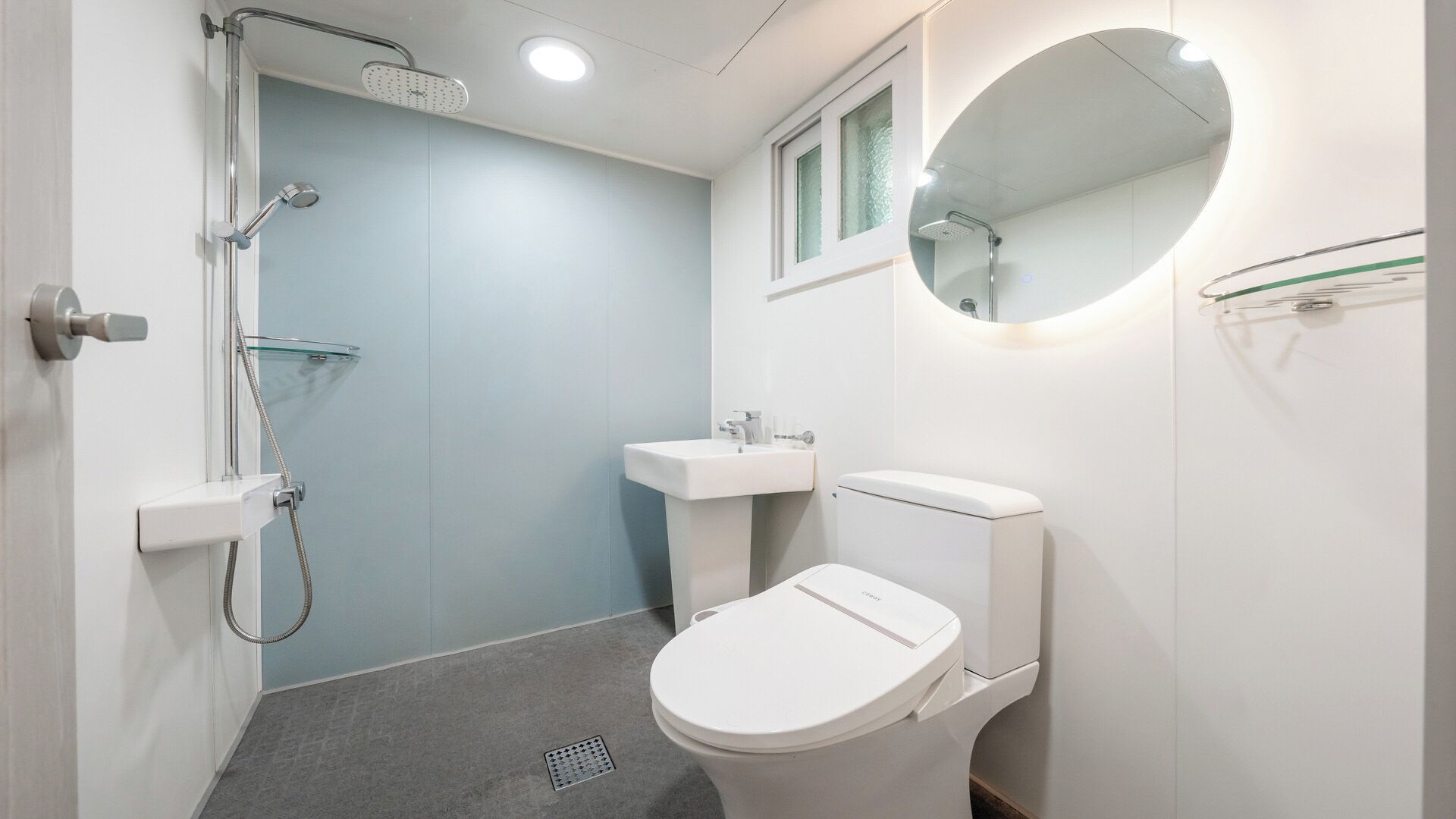 A bathroom with a shower, sink, toilet, and a mirror.