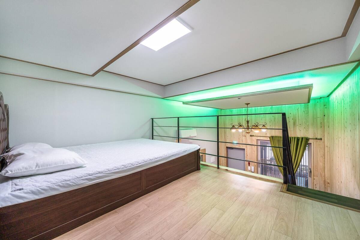 Une chambre avec un lit, une lucarne, un plancher en bois et une vue sur l’extérieur.
