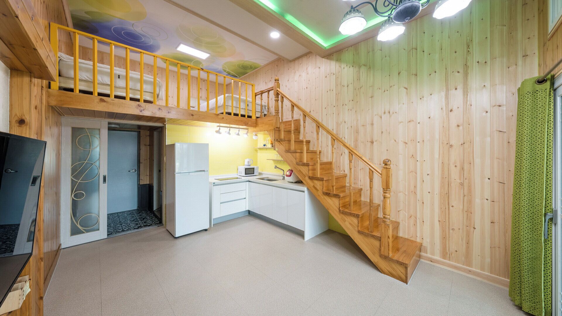 Una cocina compacta con una escalera de madera, un microondas y un refrigerador.