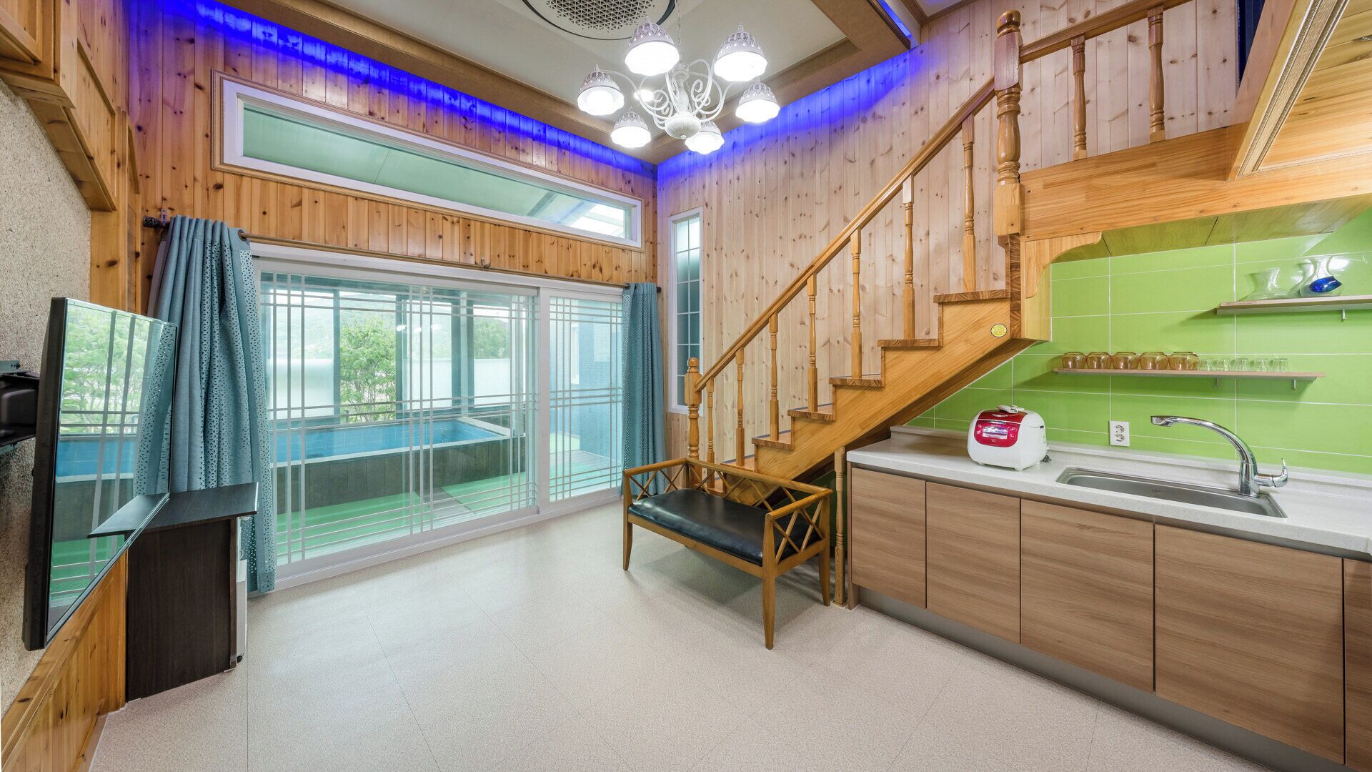 Un intérieur en bois avec un escalier, un coin cuisine et une grande fenêtre offrant une vue dégagée.