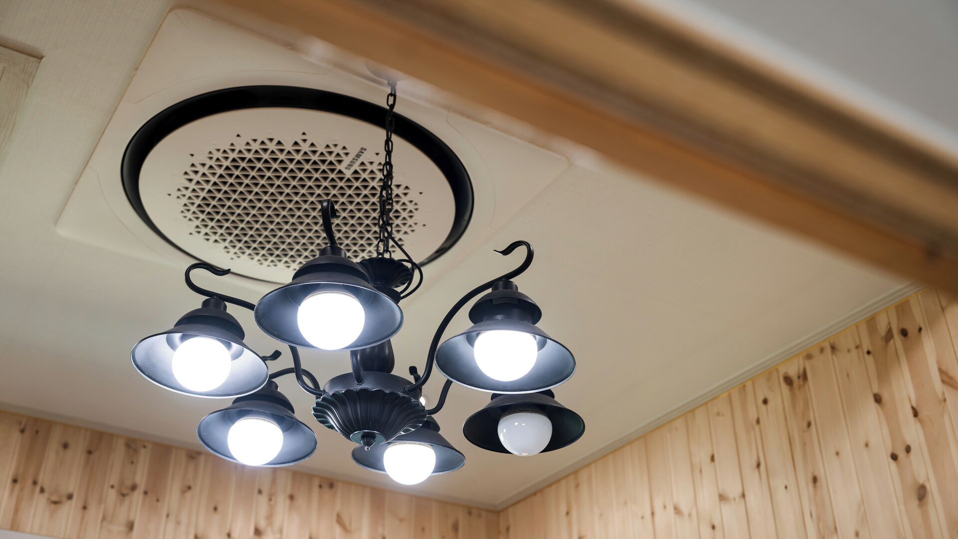 A ceiling with a central ventilation grille and four pendant lights.