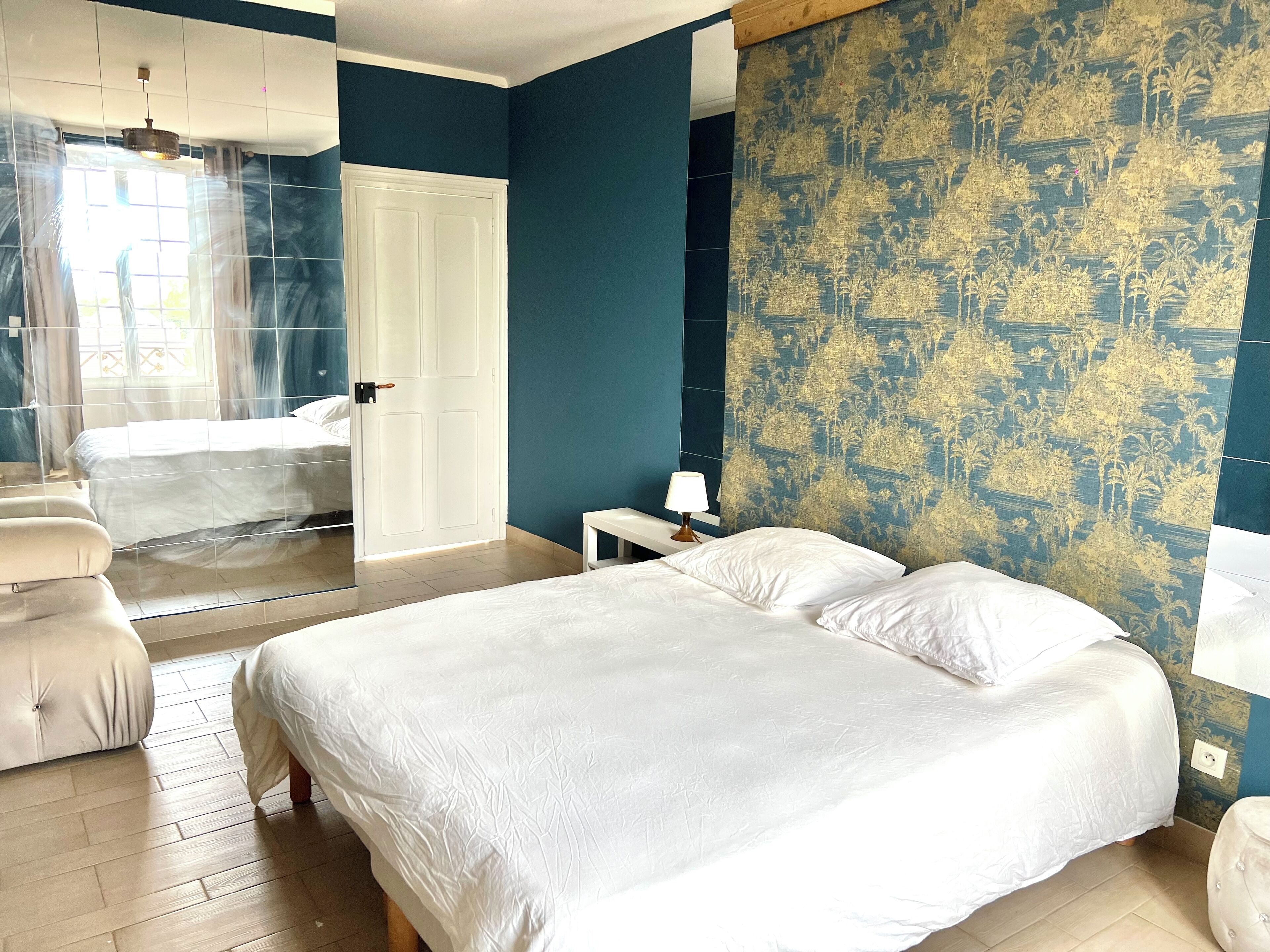 A hotel room with a bed, a chair, a nightstand, and a patterned wall.