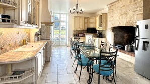 A spacious kitchen with a large island, a dining area with chairs, and a stone fireplace.