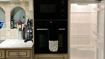 Une cuisine avec des meubles de couleur beige, un micro-ondes noir, un four et un réfrigérateur blanc.