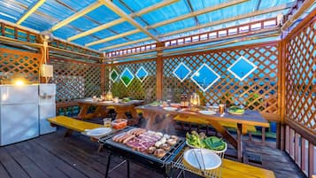 Um pátio externo com churrasqueira, mesas de jantar e um dispensador de água.