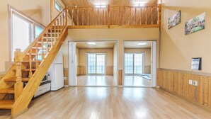 A spacious interior with a wooden staircase, large sliding glass doors, and a high ceiling. - Suncheonman Muhan Dojan Pension (Suncheon)