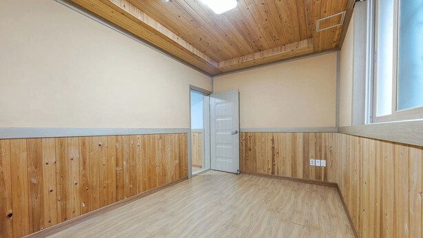A room with wooden paneling on the walls and ceiling, a door, and a window. - Suncheonman Muhan Dojan Pension (Suncheon)