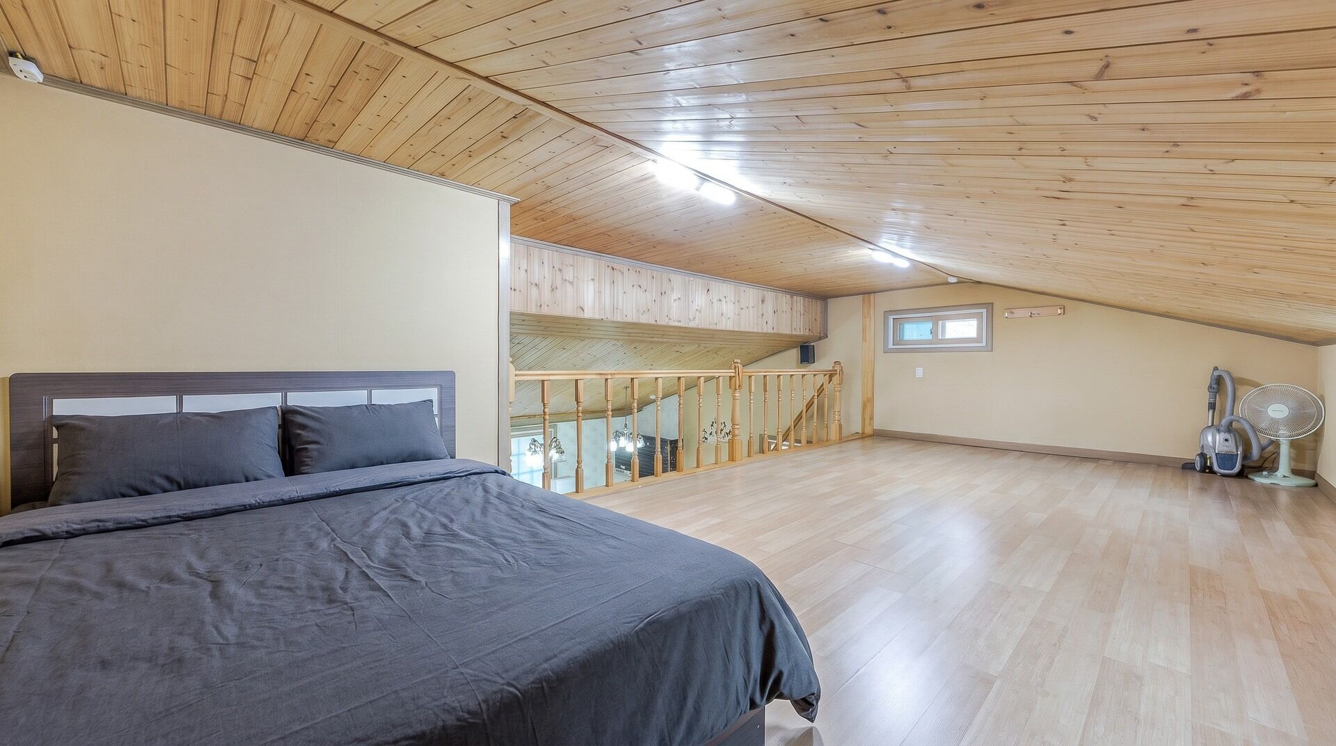 Un dormitorio con cama, techo de madera y una escalera que sube a un nivel superior.
