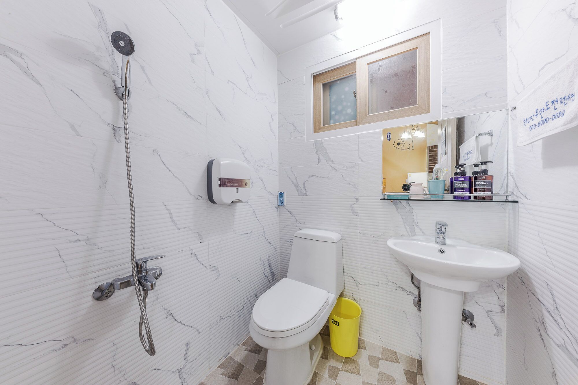 A bathroom with a white toilet, a sink, a mirror, and a shower.