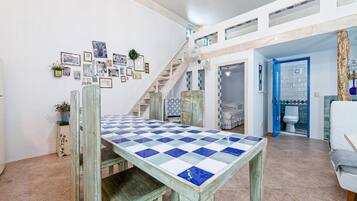 A spacious living area with a checkered table, a staircase, and a blue door leading to another room.