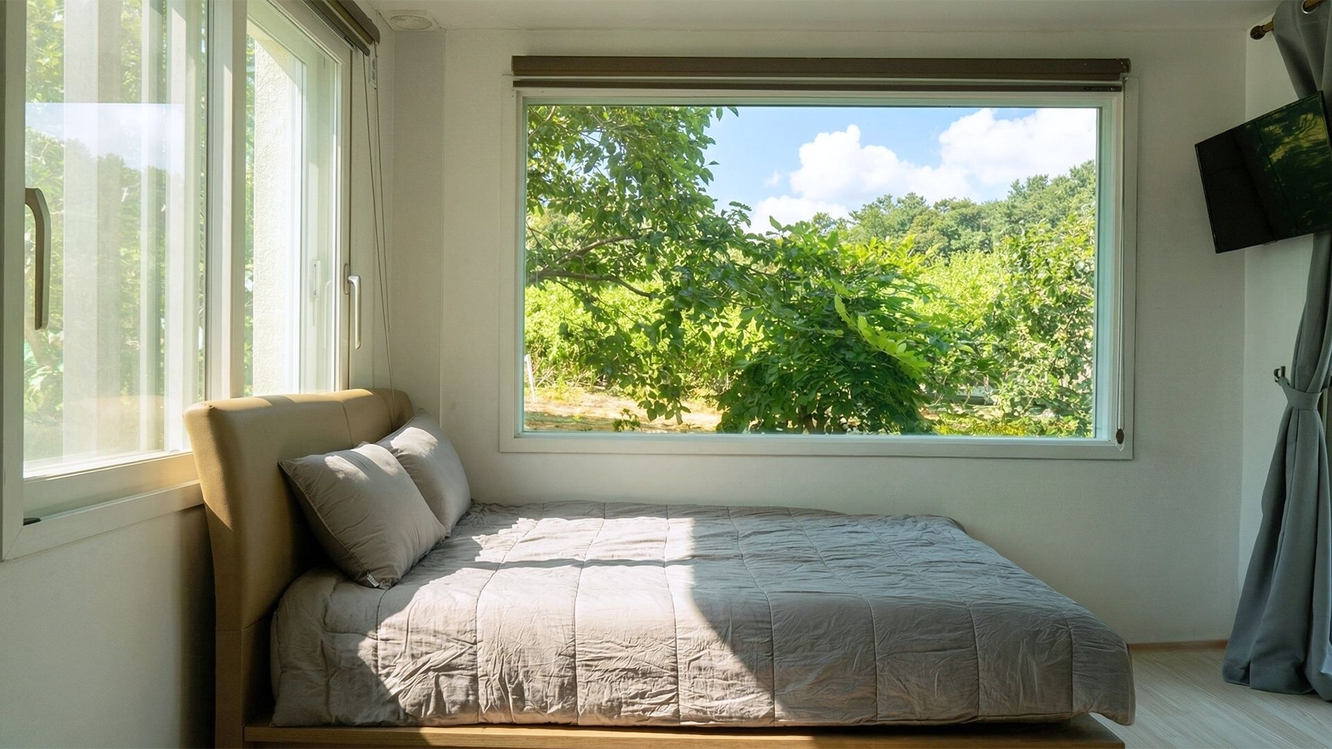 Une chambre à coucher avec un lit, une fenêtre et une vue sur la verdure.