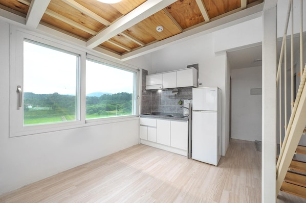 A kitchen with white cabinets, a built-in oven, and a large window offering a view of greenery. - Yangyang Slowstay Pension (Yangyang)