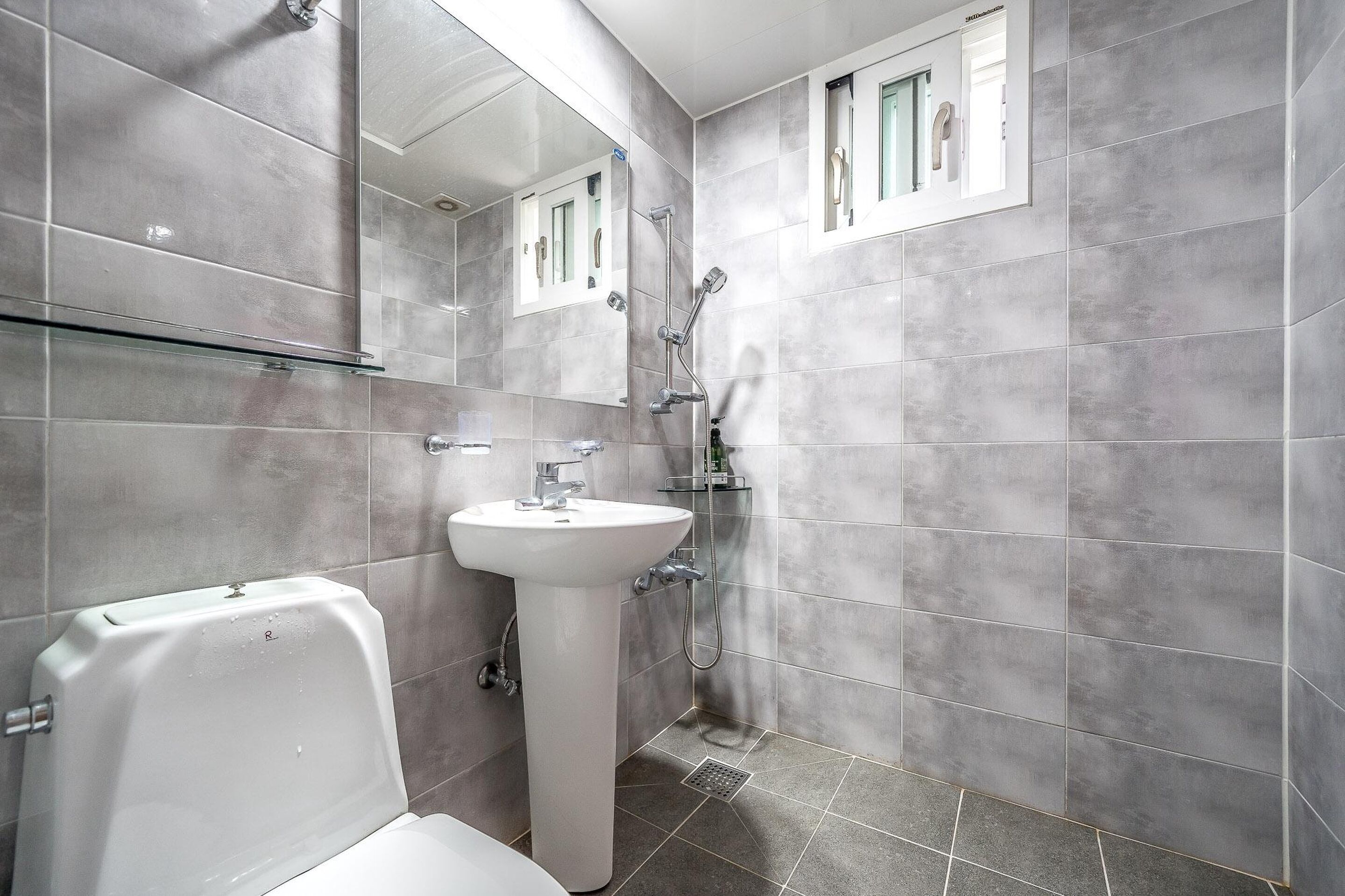 A modern bathroom with a white sink, a toilet, and a shower.