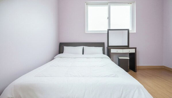 A single bed with white bedding in a room with light purple walls, a window, and a small desk with drawers. - Ganghwa Paeng Namu Pension (Incheon)