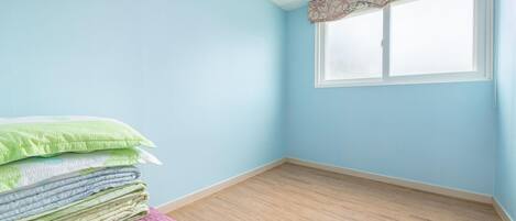 A room with light blue walls, a wooden floor, and a window with a patterned valance.