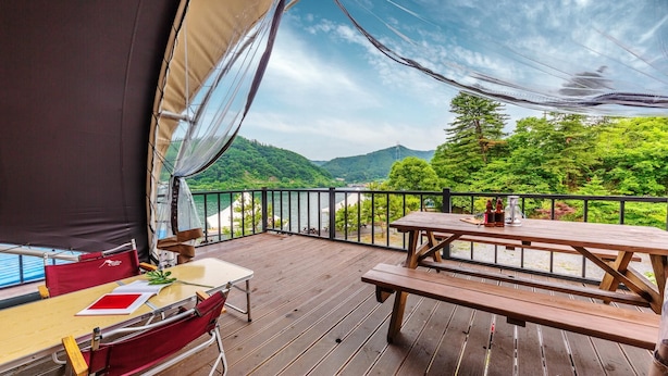 A wooden deck with a table and chairs, overlooking a body of water and green hills. - Nami Island Healing Leisure Camping&glamping (Gapyeong)