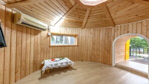 Une pièce de cabane en bois comprenant une table, une fenêtre et un appareil de climatisation.
