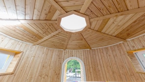 Un intérieur en bois agrémenté d’une lucarne hexagonale et d’une fenêtre centrale en arc de cercle.