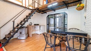A compact living space with a wooden staircase, a dining area with a table and chairs, and a large window providing a view of the outdoors. - Nami Island Healing Leisure Camping&glamping (Gapyeong)