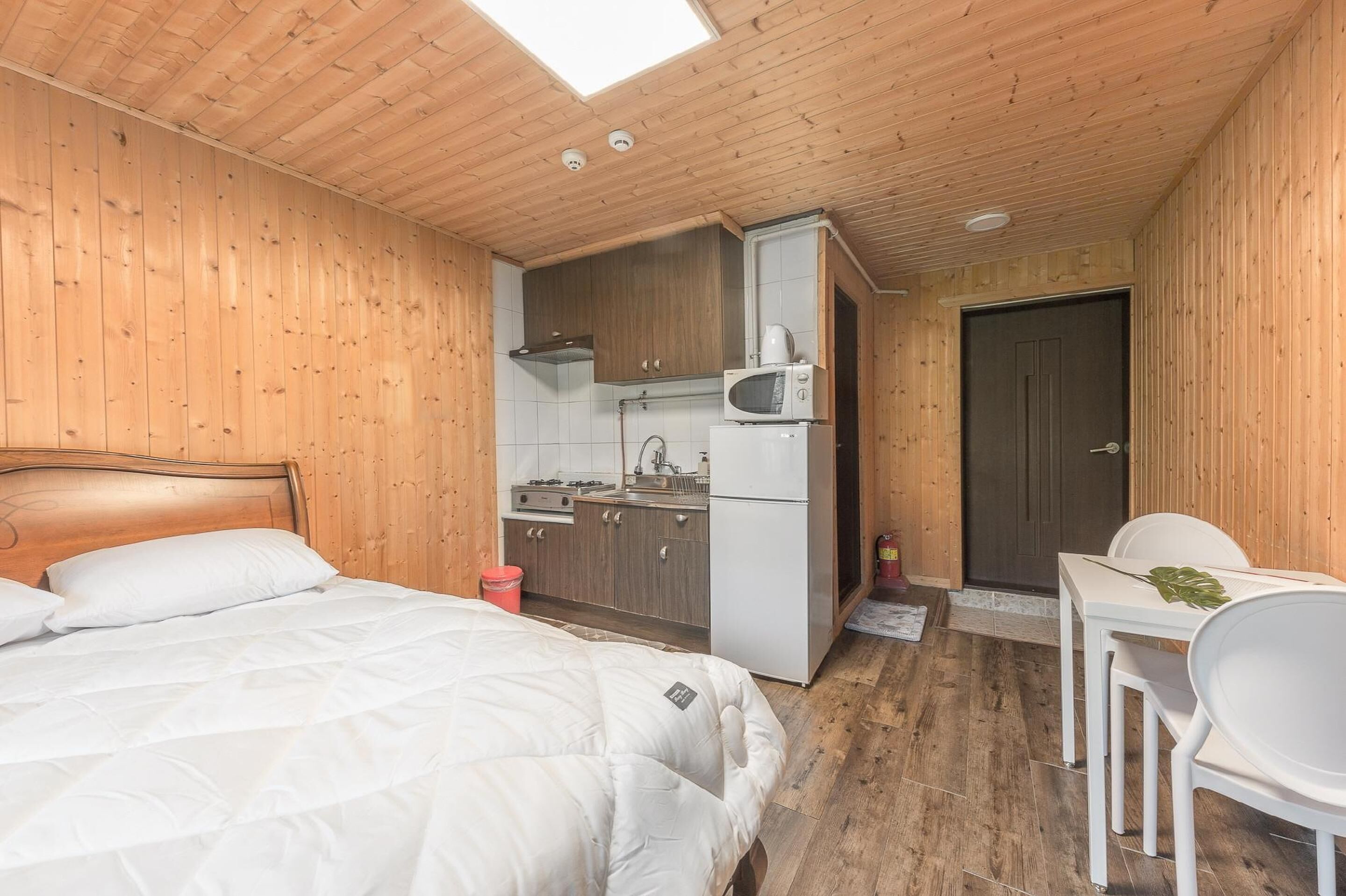 Una habitación funcional con cama, kitchenette pequeña y comedor.